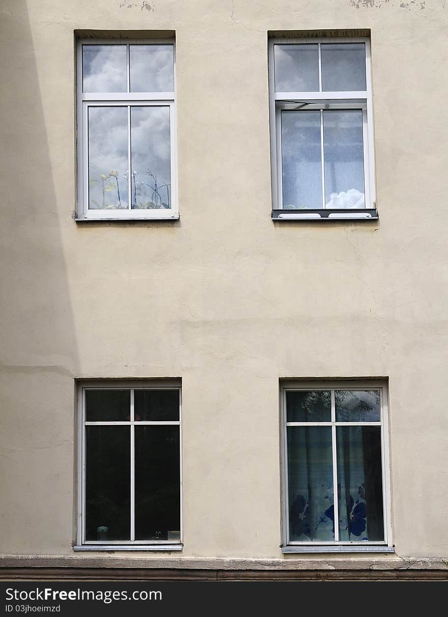 Four windows. In two windows the sky in clouds is reflected. Two other windows dark