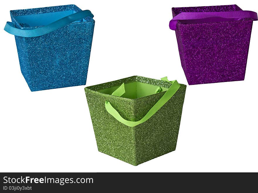 Multi-colored boxes with glitter and ribbon handles isolated on a white background. Multi-colored boxes with glitter and ribbon handles isolated on a white background.