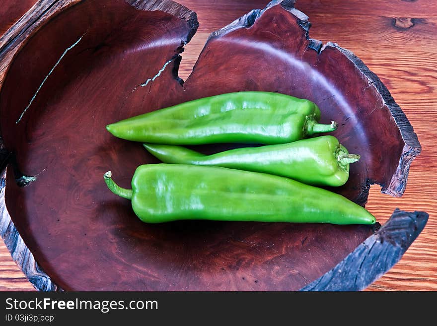 Serrano peppers in a burlwood bowl on a wood table