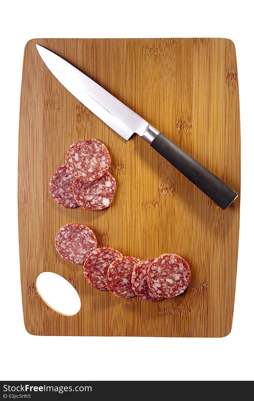 Sliced salami laying next to a knife on a brown cutting board. Sliced salami laying next to a knife on a brown cutting board.