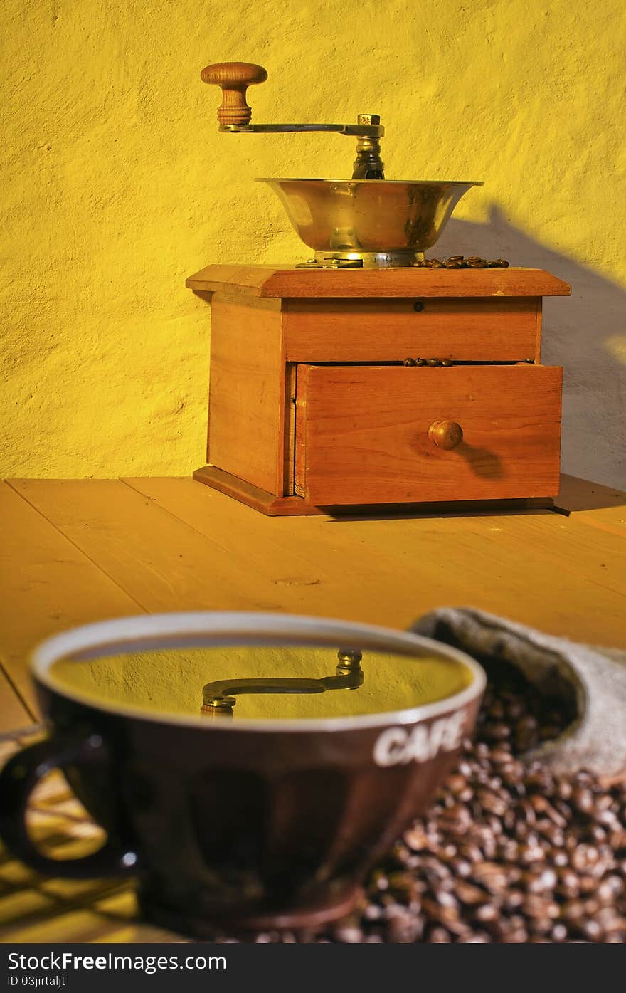 A coffee grinder and cup of coffee on the table