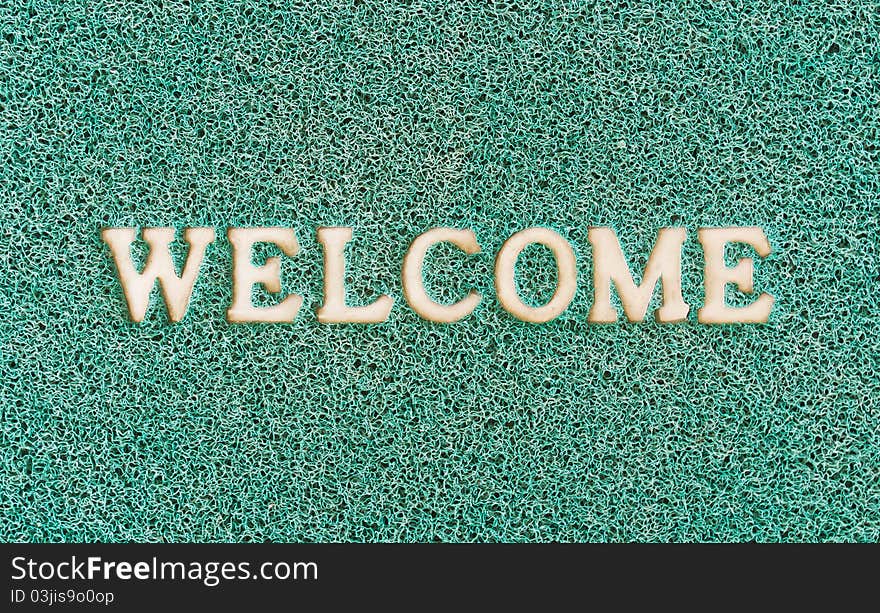 Green door mat with welcome written on it