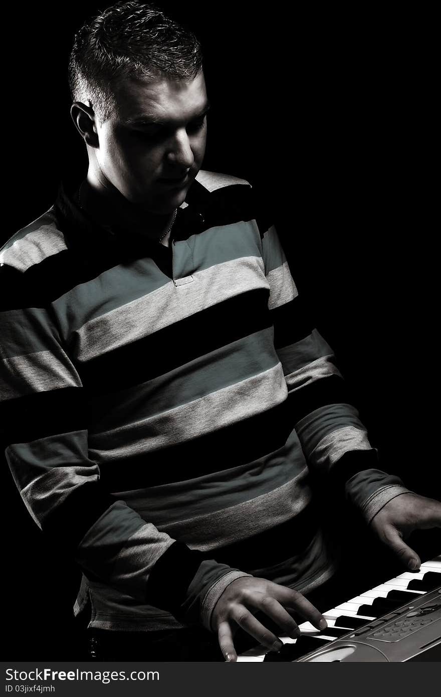 Boy plays piano, in black background, antique colors