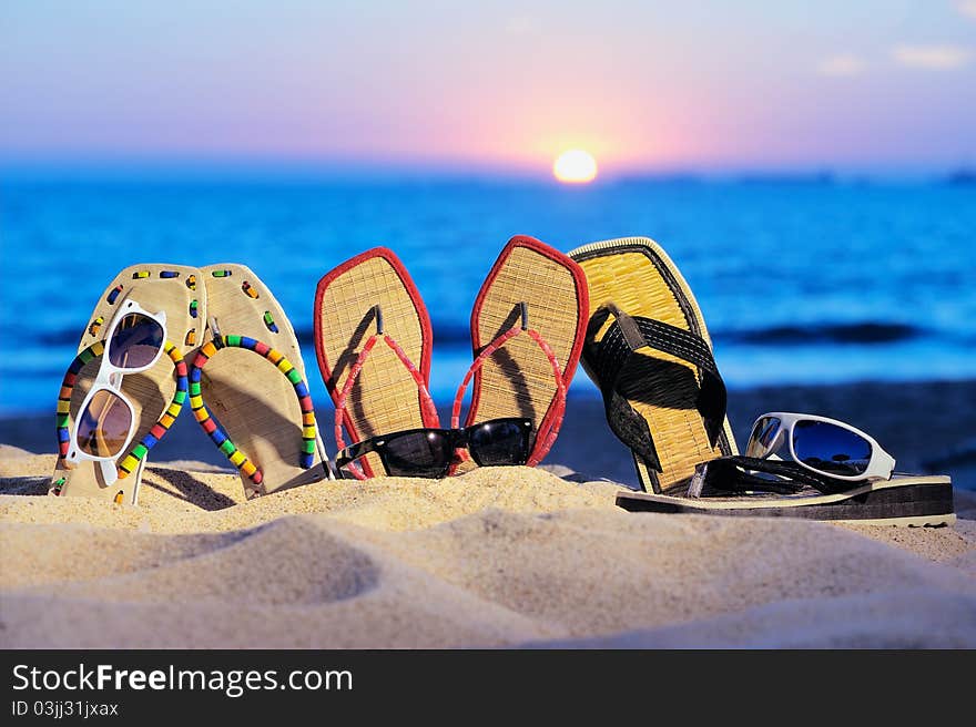 Three pair of beach sandals and glasses on the sandy beach. Three pair of beach sandals and glasses on the sandy beach