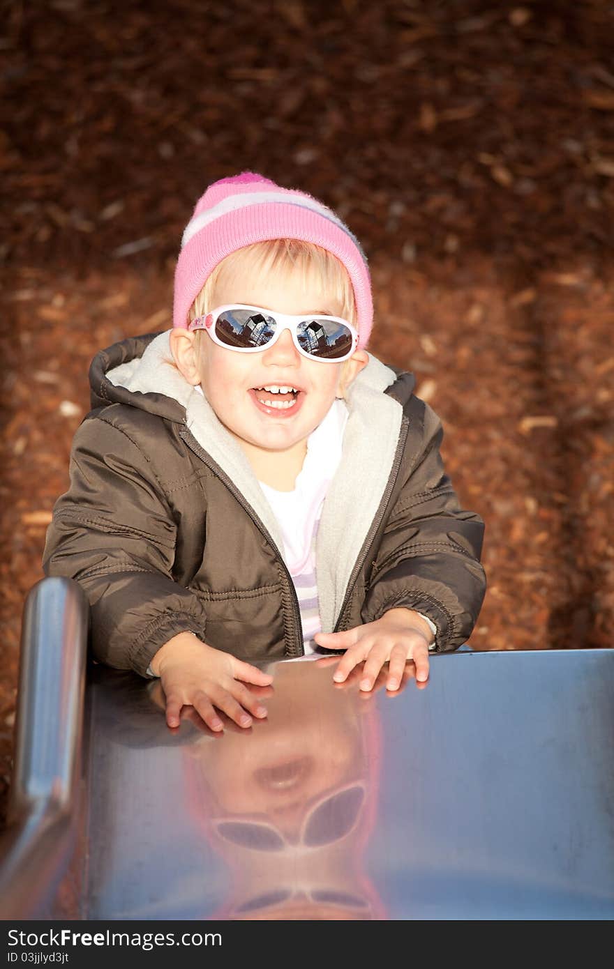 Little girl laughing at the bottom of a slippery slide. Little girl laughing at the bottom of a slippery slide