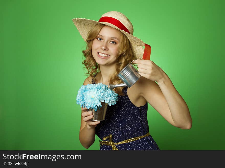 Close-up of an attractive young woman watering bouquet of chrysanthemums in a steel bucket of metal watering can. Close-up of an attractive young woman watering bouquet of chrysanthemums in a steel bucket of metal watering can