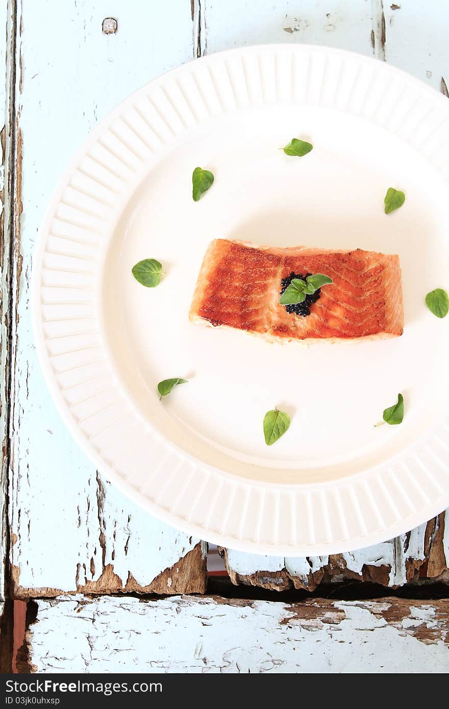 Grilled salmon fillet decorate with fresh herbs and caviar.