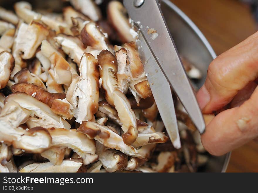 Scissors cutting fresh black mushrooms into tiny slices for food ingredients. Scissors cutting fresh black mushrooms into tiny slices for food ingredients.