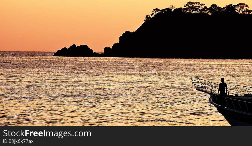 Sun setting behind a tropical island as a fisherman ties up his boat. Sun setting behind a tropical island as a fisherman ties up his boat.