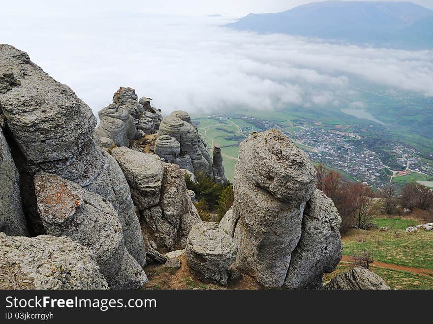 The fanciful rocks of Demirji are photographed from above. The green valley with small town is located below. The fanciful rocks of Demirji are photographed from above. The green valley with small town is located below.