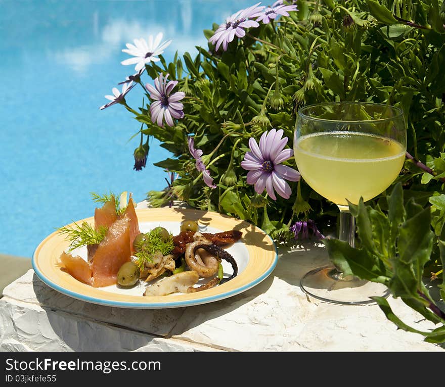 The dish with seafood salad and glass of lemon juice near poolside.Crete. Greece