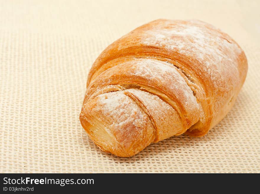 Croissant dusted with icing sugar over cloth