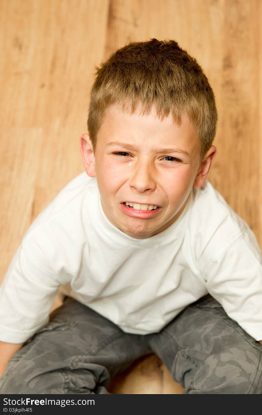 Very upset boy sitting down whilst crying. Very upset boy sitting down whilst crying