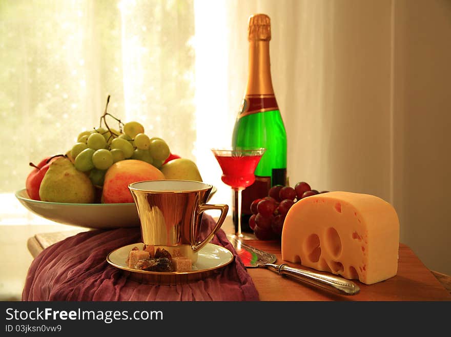 Grapes,apple,pear,cheese , glass with red wine,bottle and coffee in glold cup, on blurred background. Grapes,apple,pear,cheese , glass with red wine,bottle and coffee in glold cup, on blurred background.