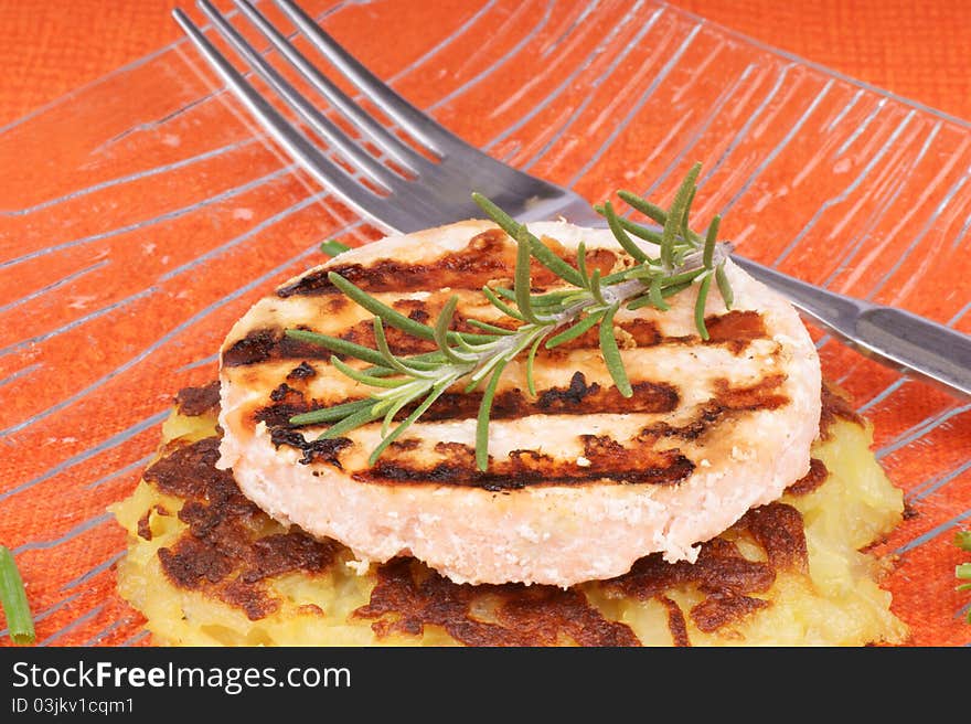 Grilled salmon and roesti with chives and rosemary over a glass dish. Selective focus, shallow DOF