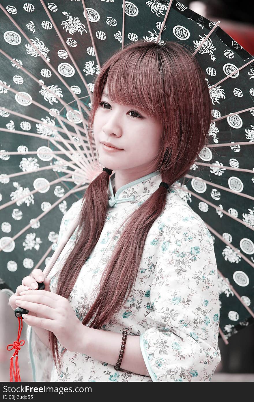 Chinese beauty in traditional dress holding an Chinese umbrella outdoor. (Close-up) Ancient Chinese characters on the umbrella are Good fortune and life. Chinese beauty in traditional dress holding an Chinese umbrella outdoor. (Close-up) Ancient Chinese characters on the umbrella are Good fortune and life.