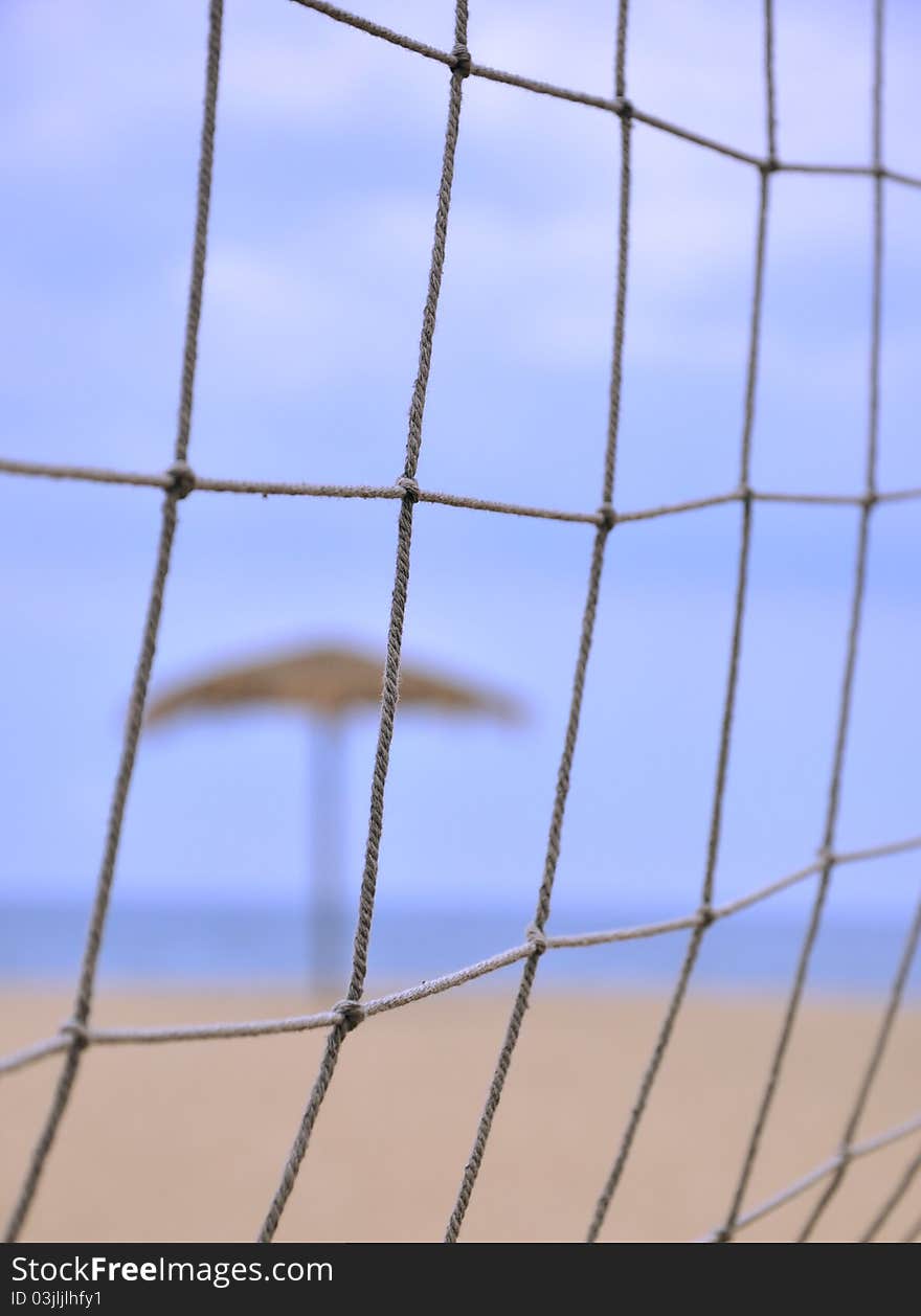 Sunshade behind sand volleyball net on beach