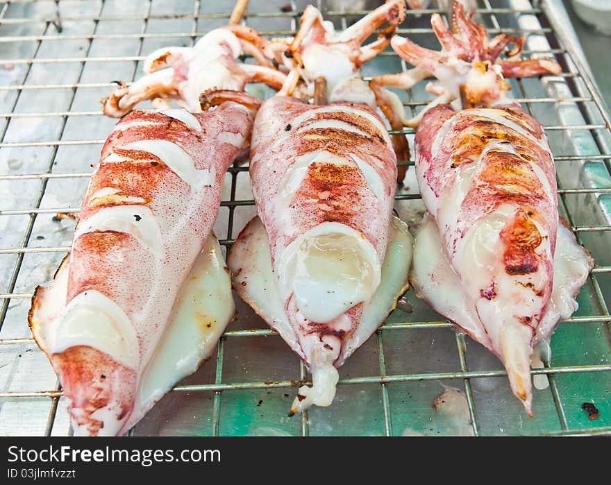 Three squid with a wooden plug. To take to the grill. Three squid with a wooden plug. To take to the grill