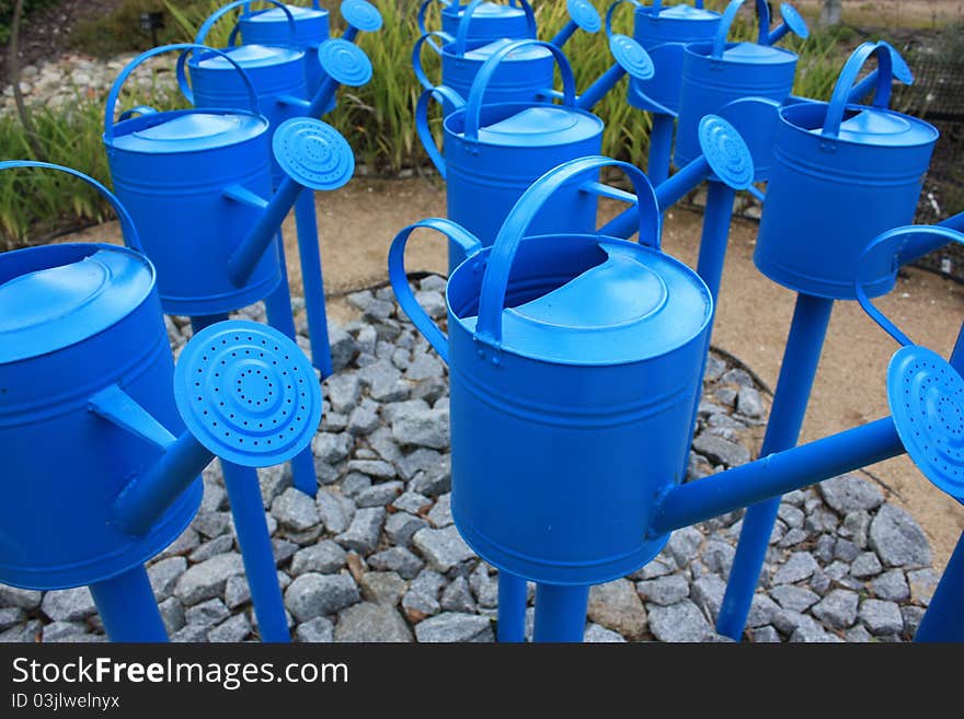 Three rows of Blue watering cans.