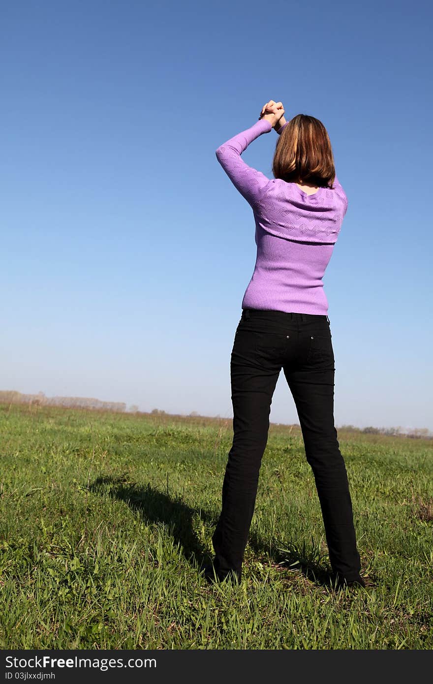 Close up of the girl holding hands compressed in fist above a head on a green meadow. Close up of the girl holding hands compressed in fist above a head on a green meadow.