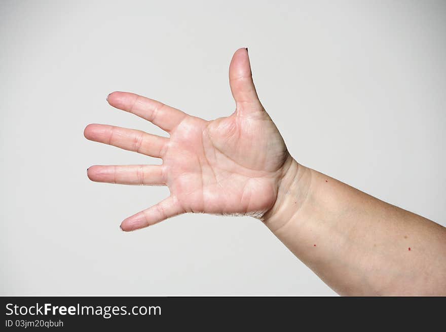 A woman holding her arm out and showing all of her fingers against a white background. A woman holding her arm out and showing all of her fingers against a white background.