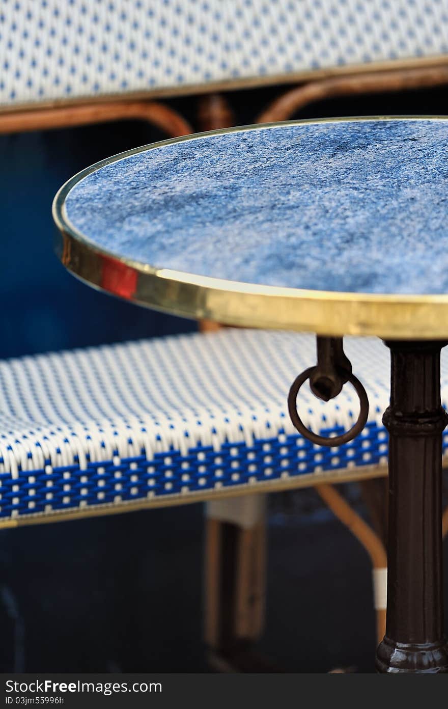 Table and wicker chair in cafe in Paris. Photo with tilt-shift effect