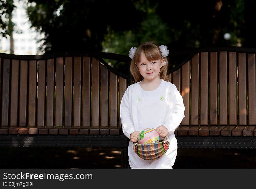 Adorable small girl with long dark hair in colorful warm clothes looks into the camera