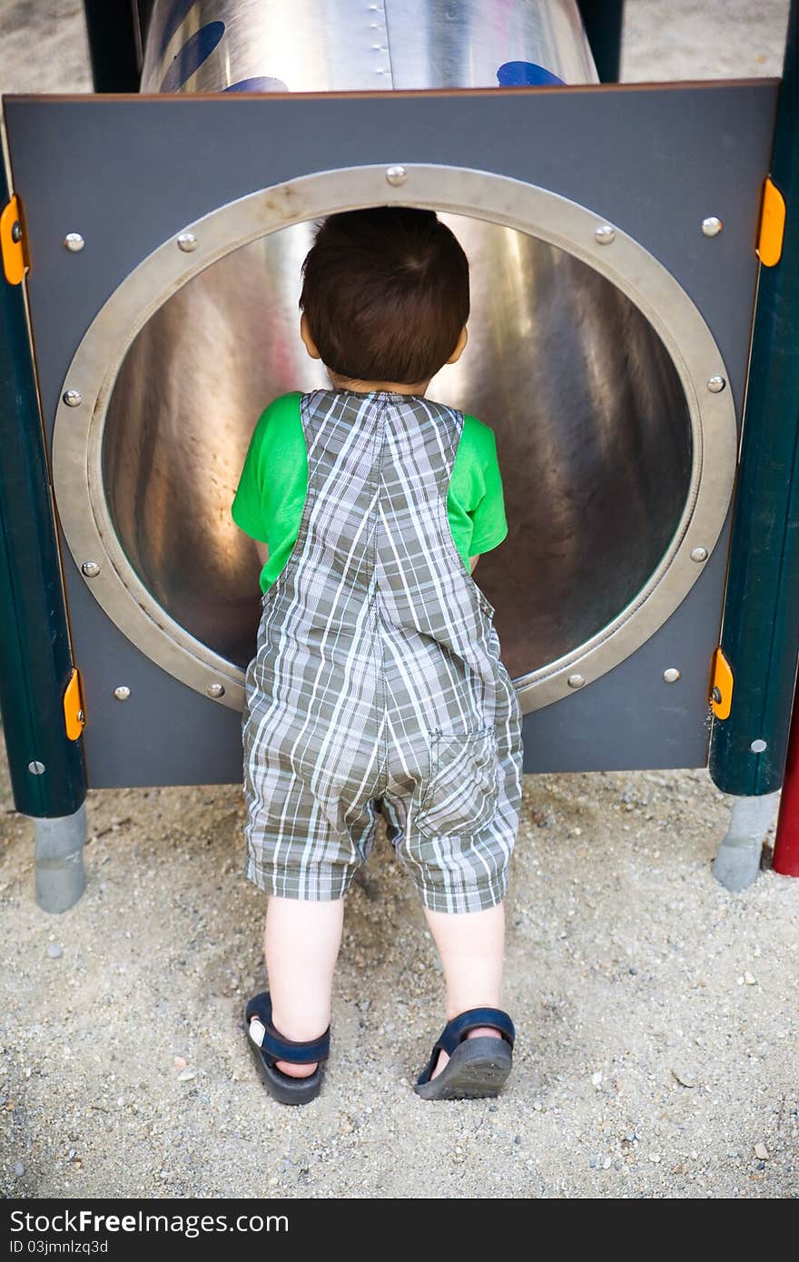 Child exploring a pipe tunnel in playground. Child exploring a pipe tunnel in playground