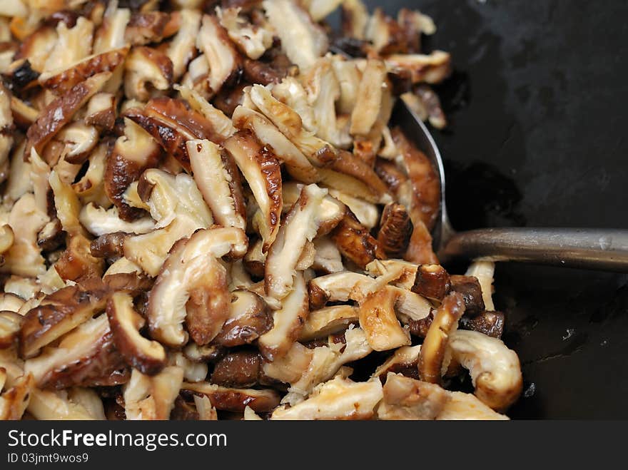 Cooking fragrant mushroom slices in traditional Chinese wok. Cooking fragrant mushroom slices in traditional Chinese wok.