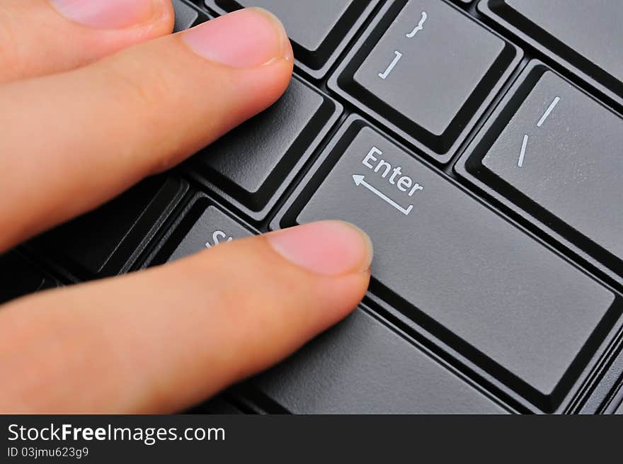 Left hand fingers pressing on black Enter key on computer keyboard. Left hand fingers pressing on black Enter key on computer keyboard.