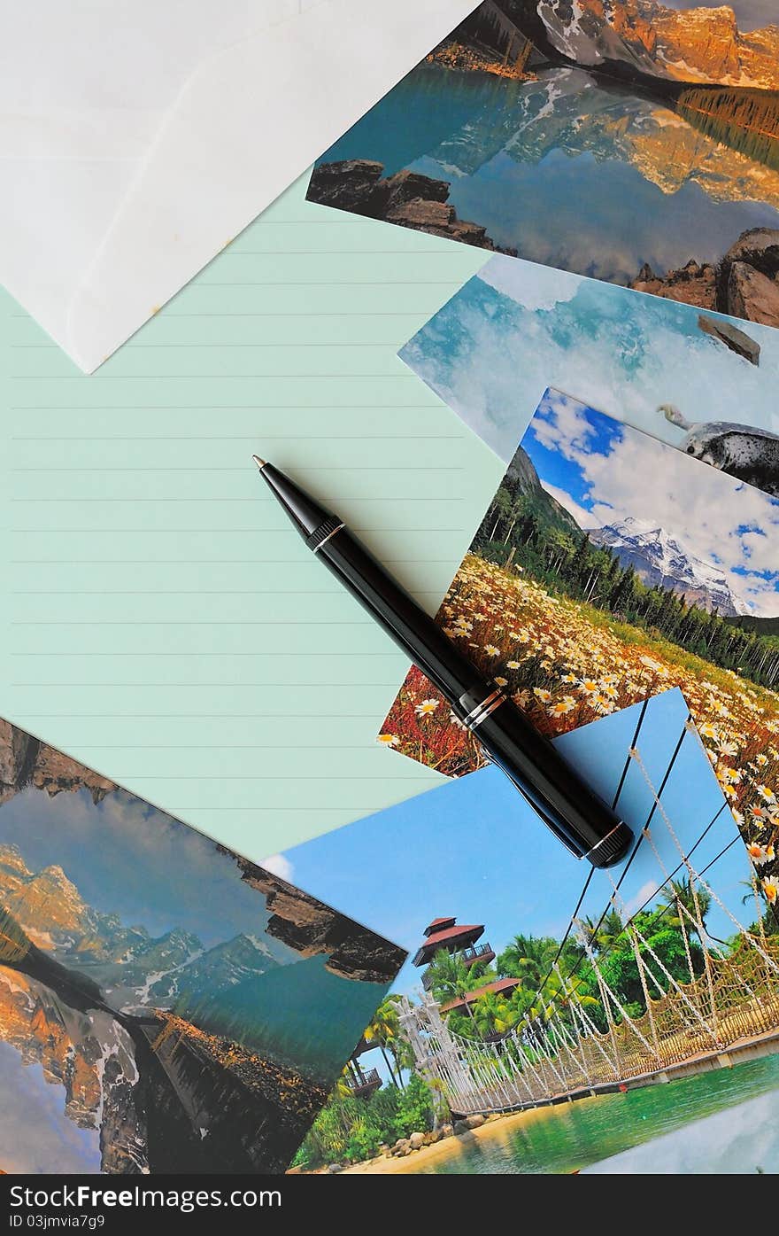 Empty letter pad and pen with scenic postcards in background. Empty letter pad and pen with scenic postcards in background.