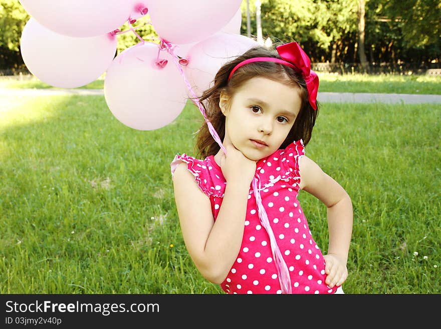 Close-up of a little girl standing in the park with pink balloons. Close-up of a little girl standing in the park with pink balloons