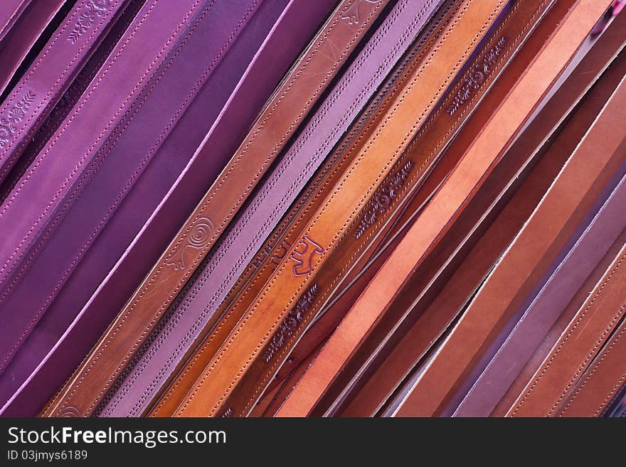 Leather belts being sold at the local market, forming a colorful diagonal pattern.