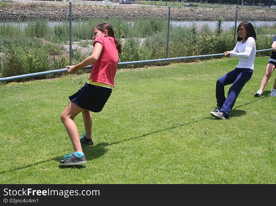 Two girls pulling a rope in a tug-o-war.