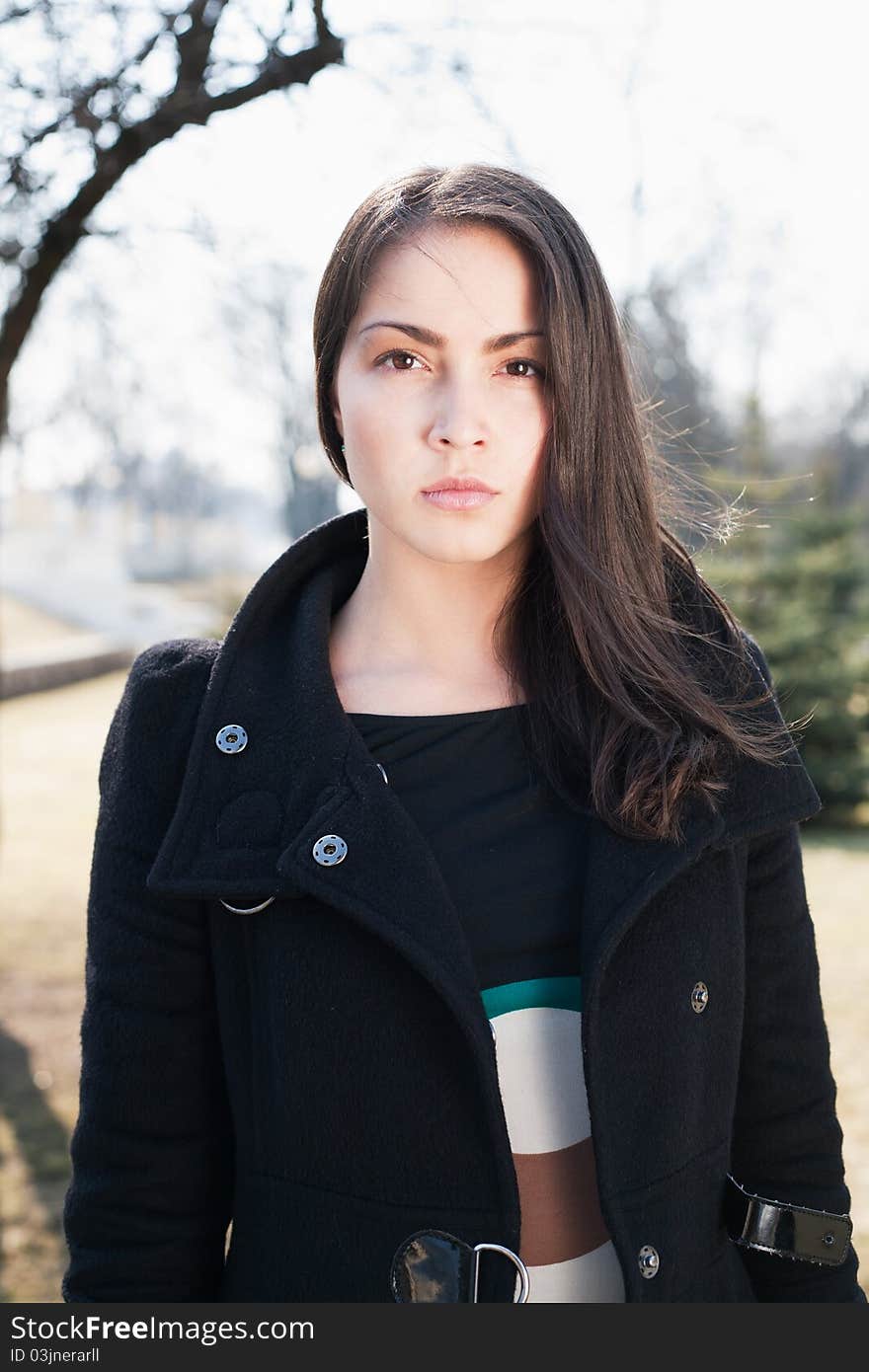 A beautiful woman in the coat standing on the street.