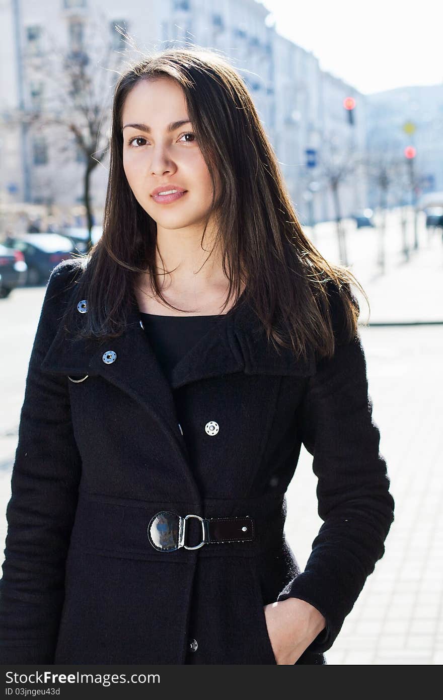 A beautiful woman in the coat standing on the street.