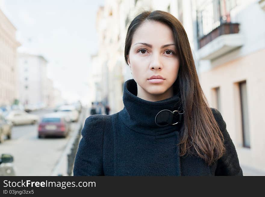 A beautiful woman in the coat standing on the street.