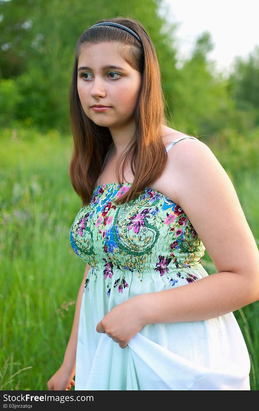 The portrait of beautiful young girl in light dress on a the summer green background