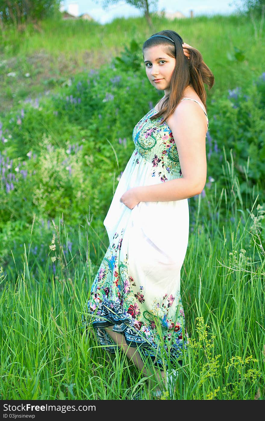 The portrait of young girl in light dress on a the summer green background