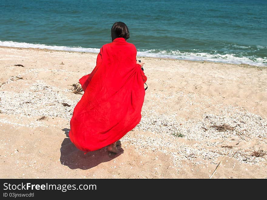 Girl in big red pareo walking on the beach. Girl in big red pareo walking on the beach