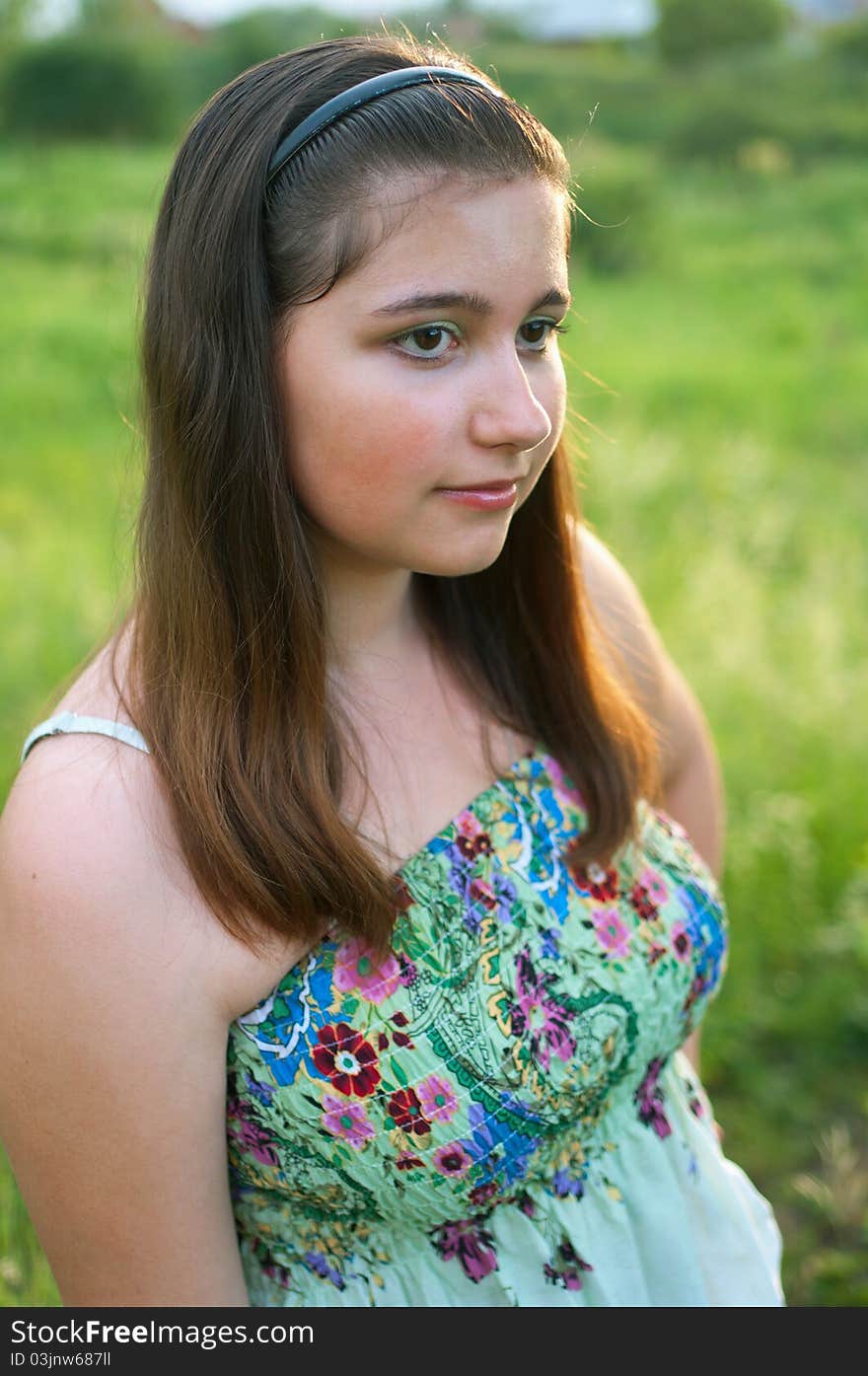 The portrait of young girl in light dress on a the summer green background