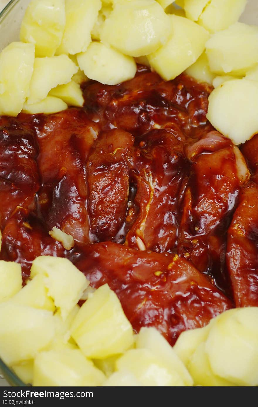 Marinated raw meat in a pile of raw potatoes prepared for baking. Marinated raw meat in a pile of raw potatoes prepared for baking