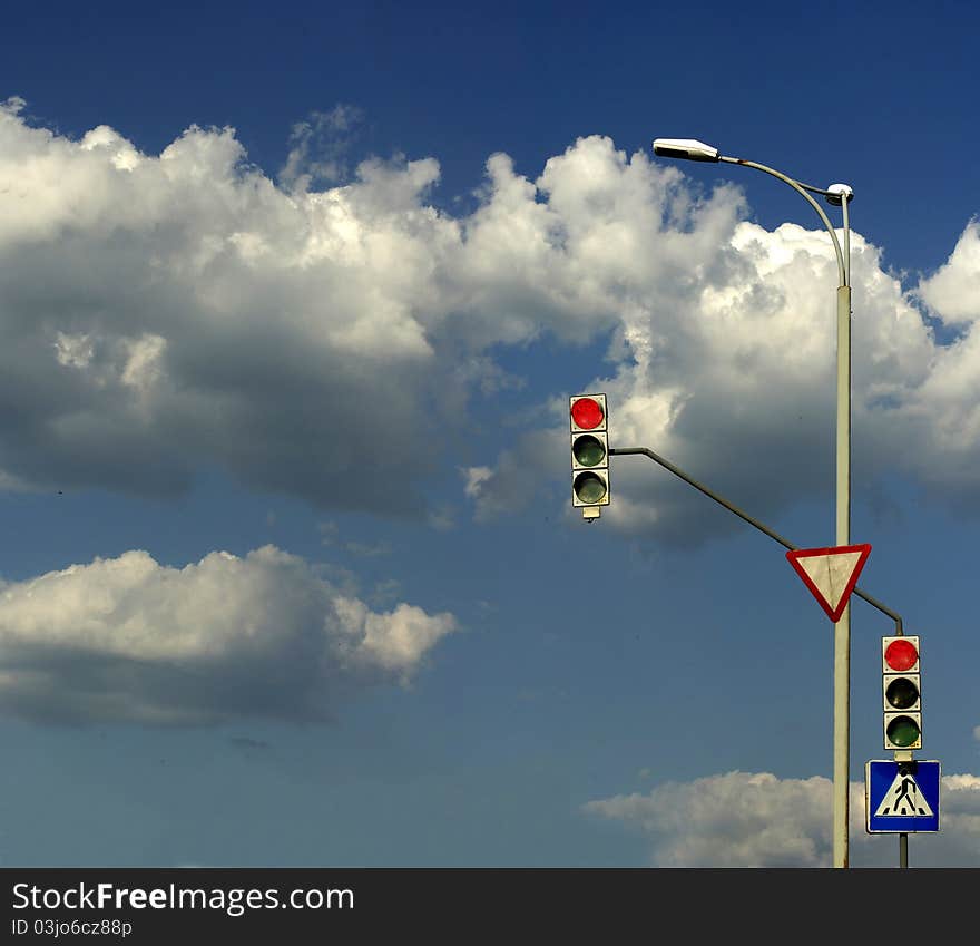 Stoplight against the sky with clouds