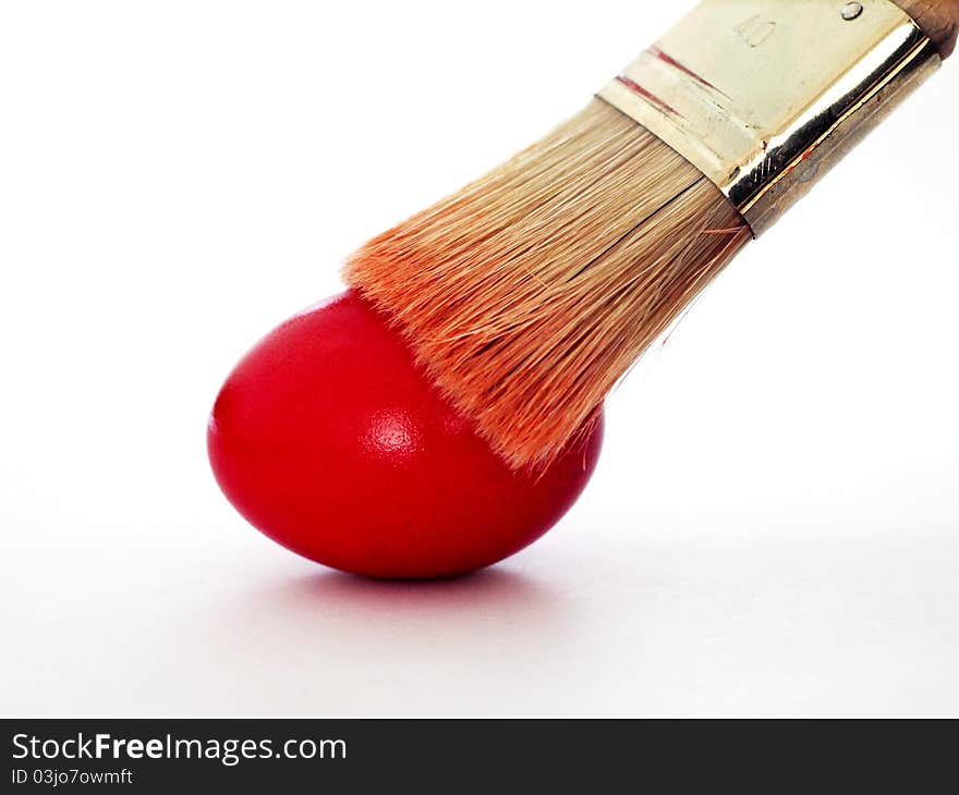 A brush painting a red easter egg. A brush painting a red easter egg