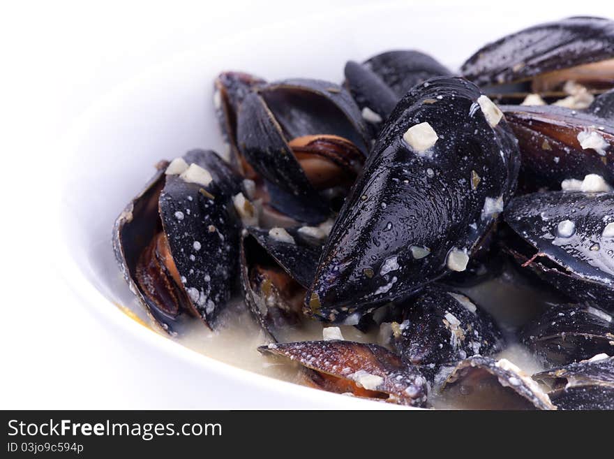 Close up picture of mussels in the bowl in white background.