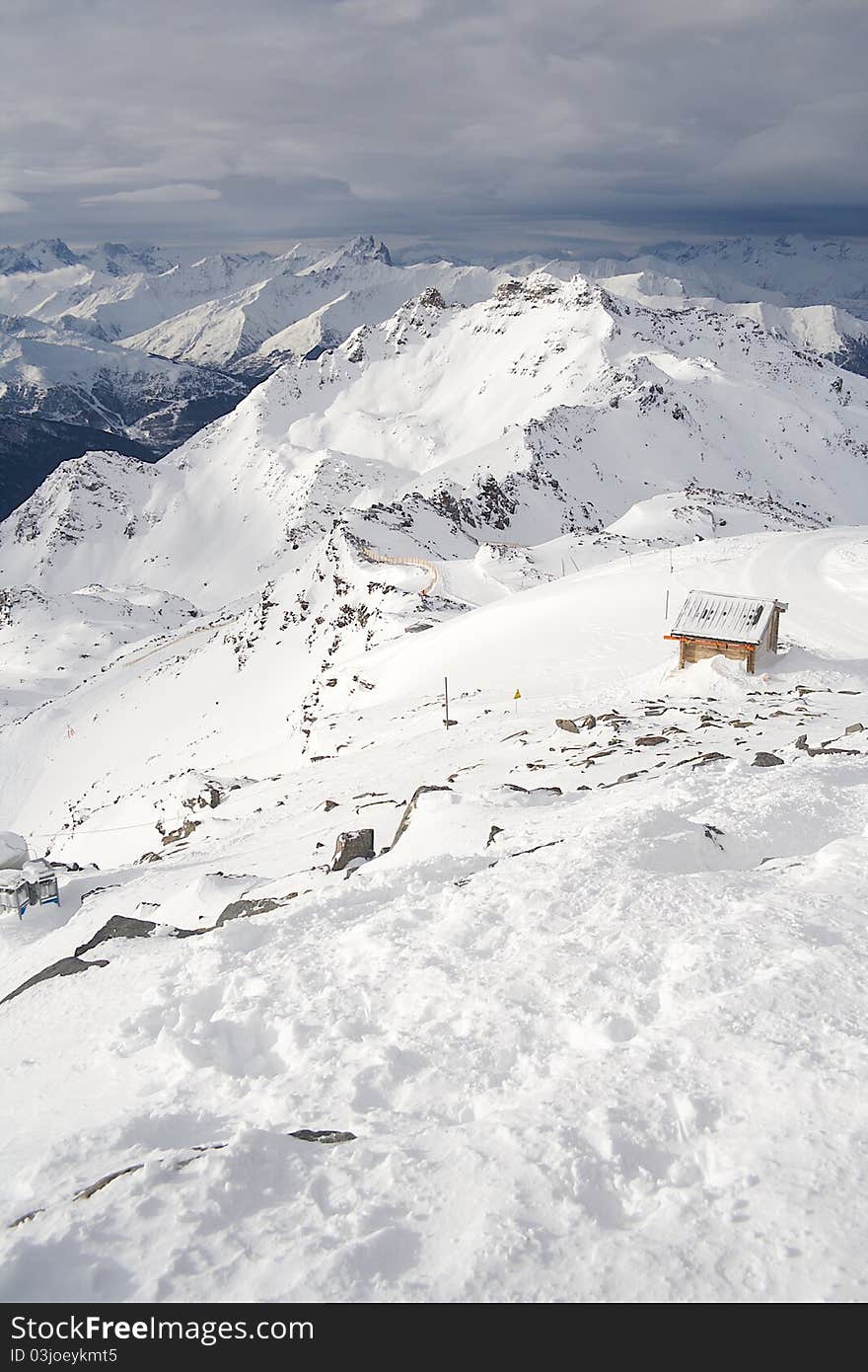 A snowy ridge in the alps with a mountain hut. A snowy ridge in the alps with a mountain hut.