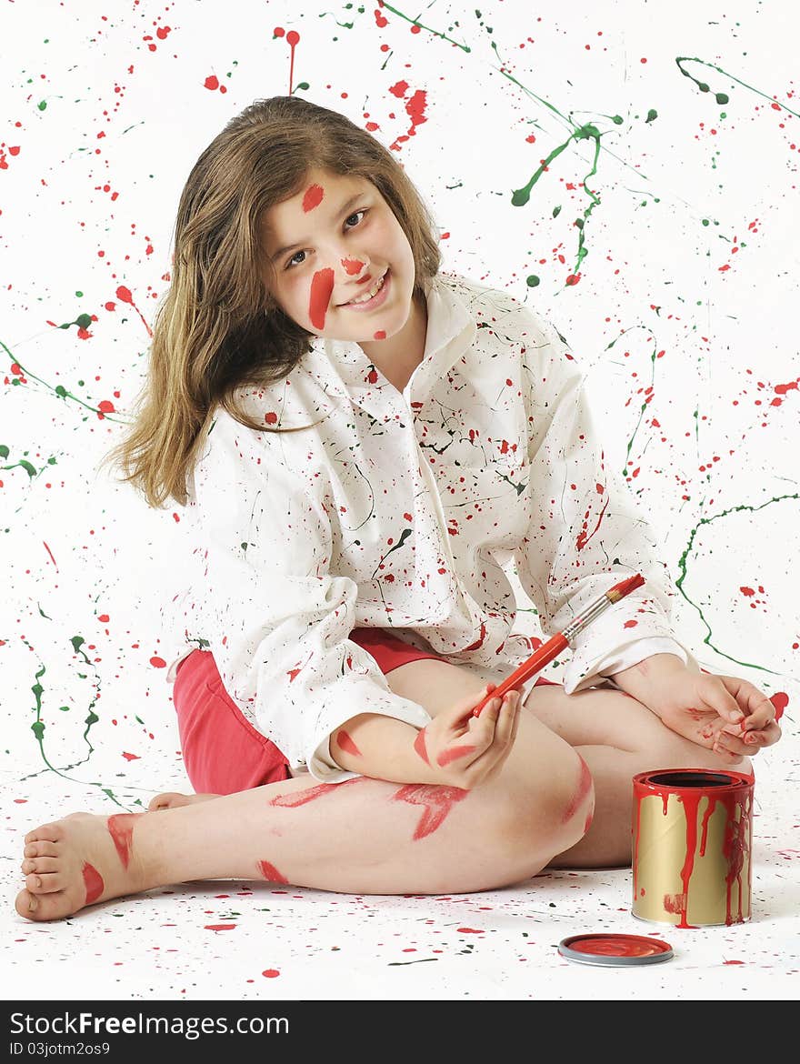 An attractive preteen girl painting red in a white shirt and background spashed in Christmas colors. An attractive preteen girl painting red in a white shirt and background spashed in Christmas colors.