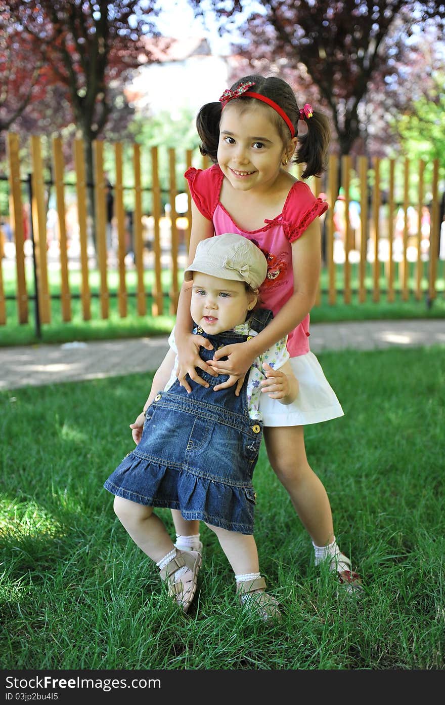 Two sisters sitting outdoors smiling and hugging. Two sisters sitting outdoors smiling and hugging