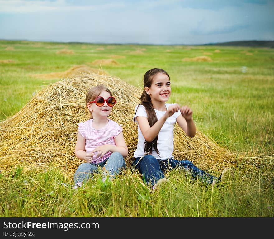 Two happy little sisters having fun in the summer day in field