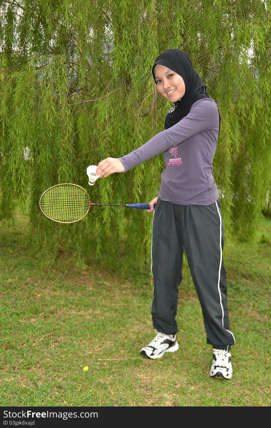 Young woman doing outdoor exercises with badminton racket. Young woman doing outdoor exercises with badminton racket